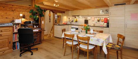 Un interior de madera acogedor con comedor, cocina y estantería.