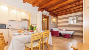 Un comedor con una mesa dispuesta para cuatro, sillas de madera y un sofá rojo al fondo.