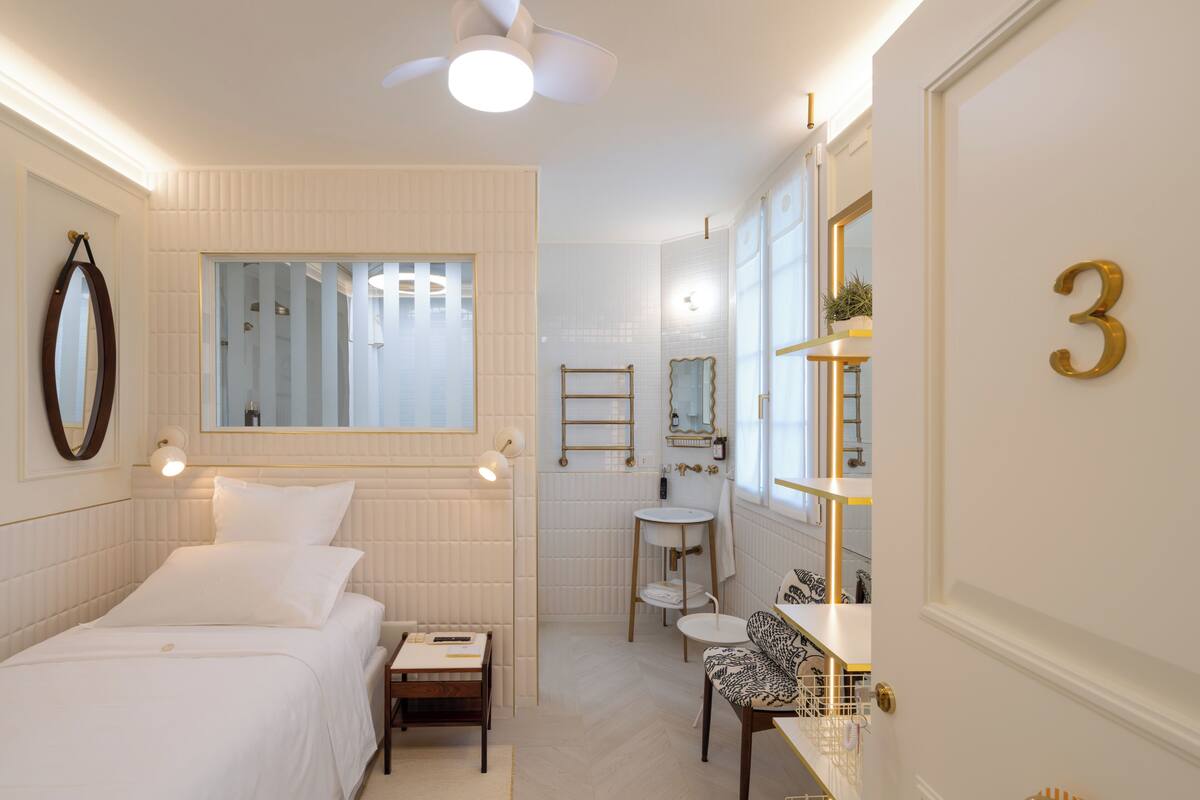 Une chambre d’hôtel comprenant un lit, une table de chevet, une coiffeuse avec miroir et un petit coin salon.