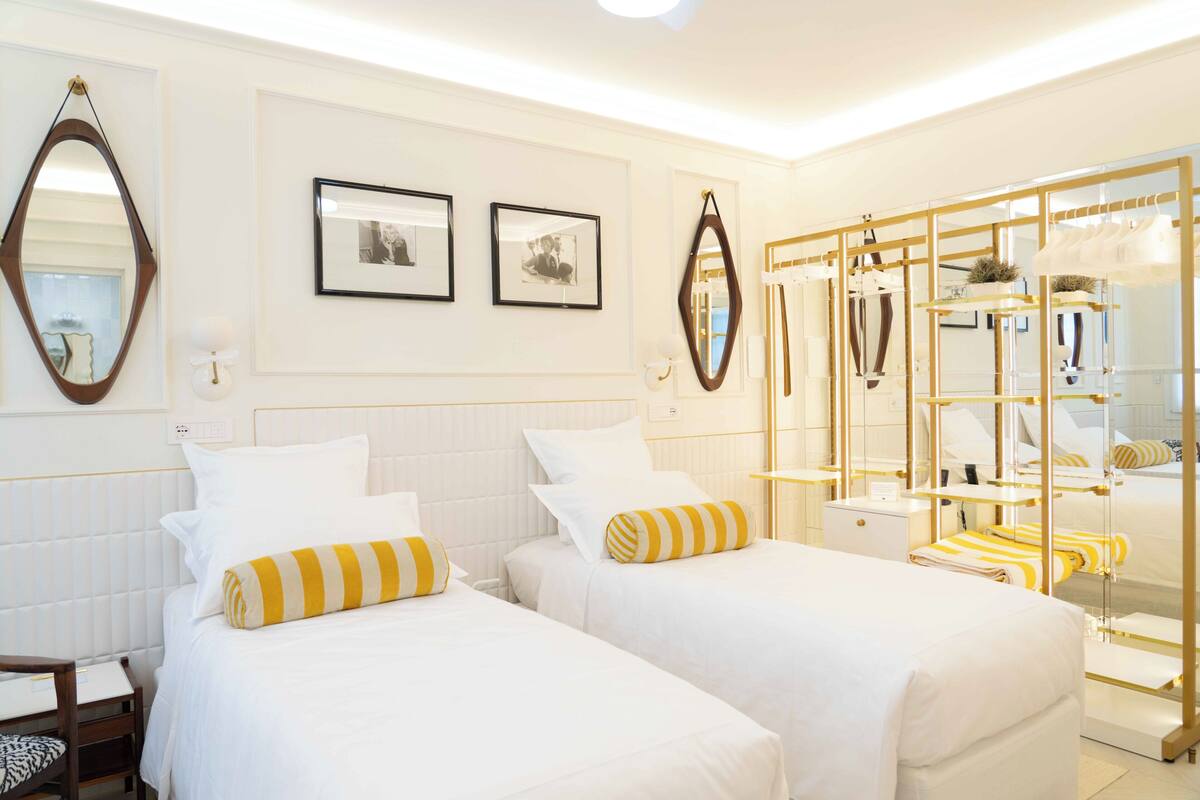 Une chambre d’hôtel avec deux lits, une armoire et un miroir.