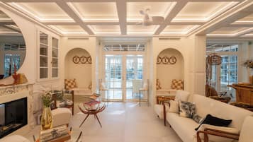 A spacious living room with a fireplace, seating area, and a view through the glass doors.