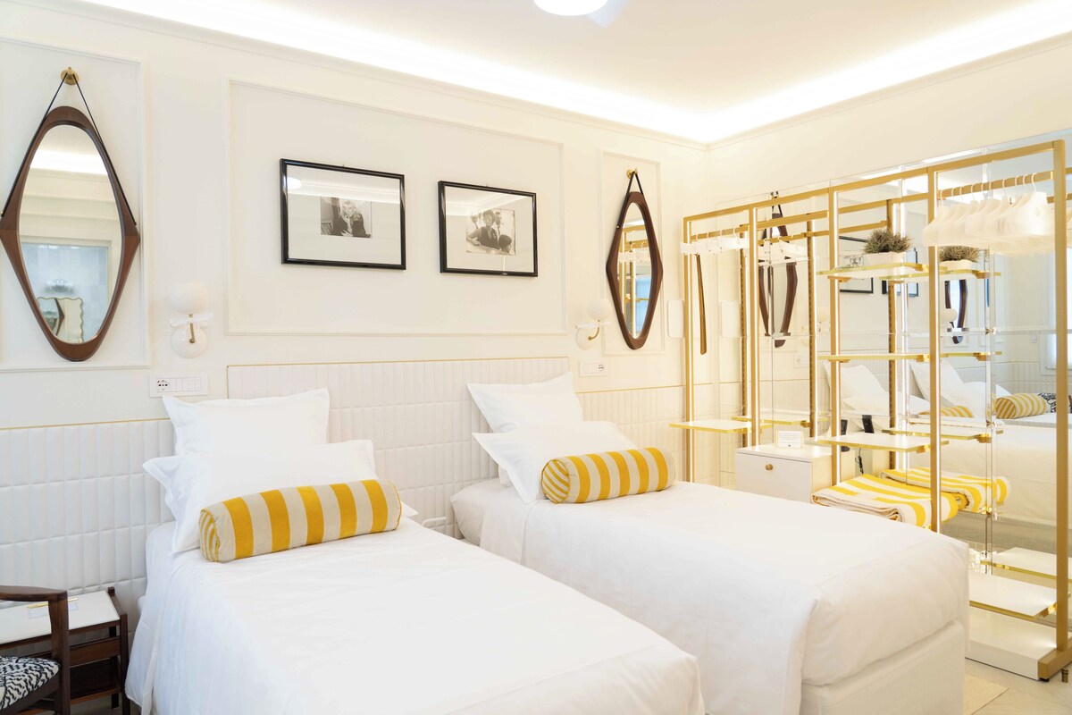 Habitación de hotel con dos camas, un armario y un espejo.