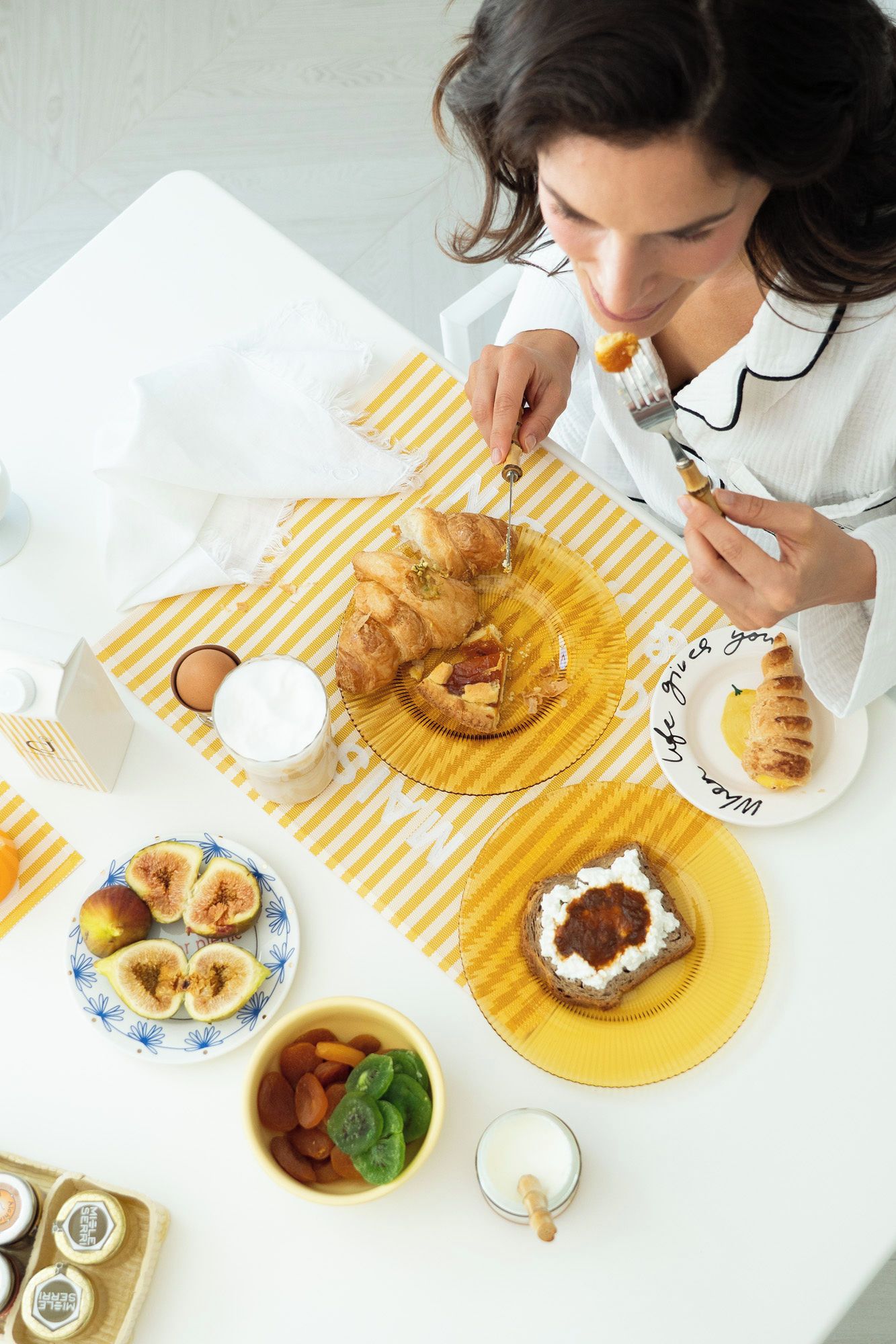 A breakfast setting with croissants, figs, and a plate with a message.