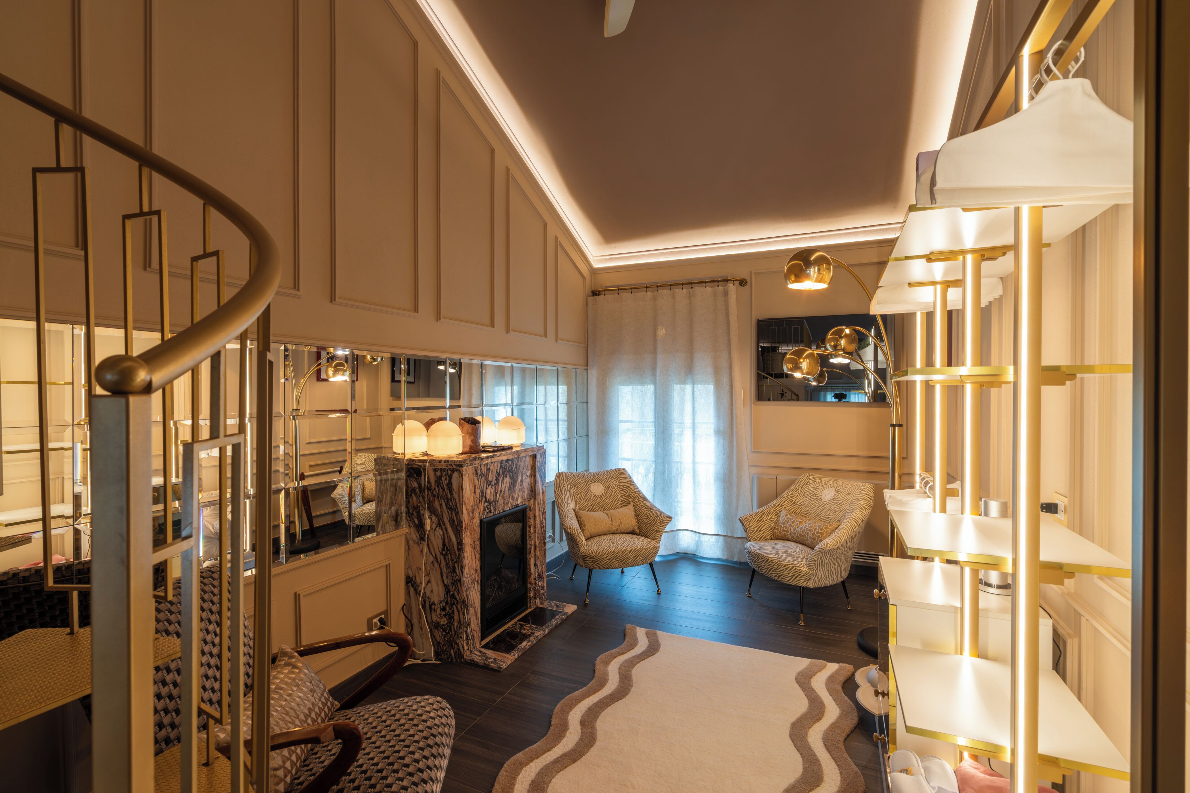 A spacious room with a marble fireplace, a curved staircase, and a modern chandelier.