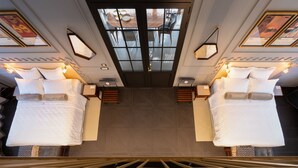 Ett hotellrum med två sängar, ett stort fönster och utsikt över staden.