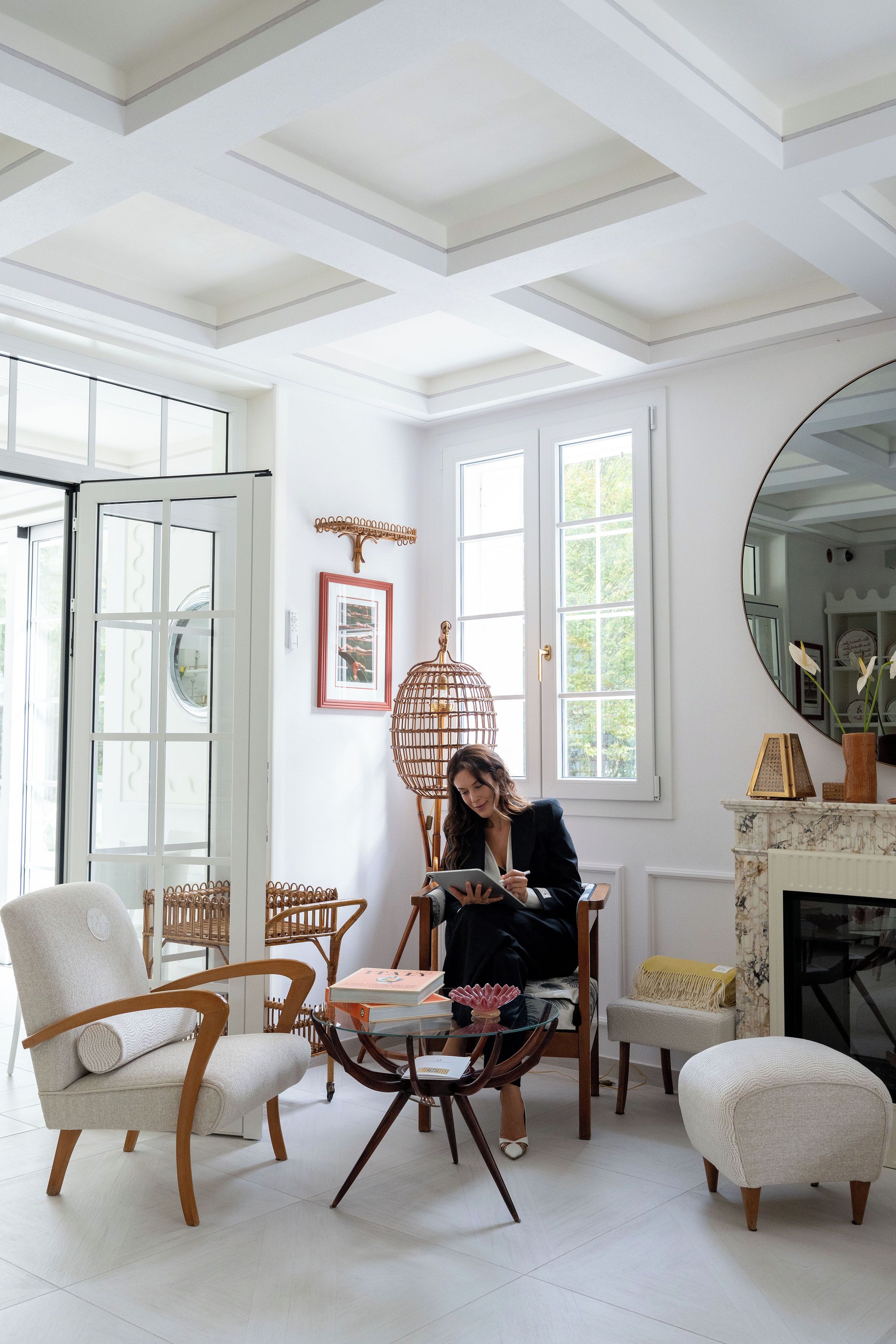 A room with a white ceiling, large windows, a fireplace, and a dining area with chairs and a table.
