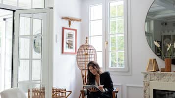 A room with a white ceiling, large windows, a fireplace, and a dining area with chairs and a table.