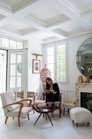 Una habitación con techo blanco, ventanas amplias, chimenea y un comedor con sillas y mesa.