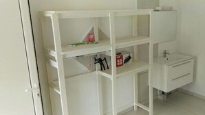 Ein helles Badezimmer mit integriertem Regalschrank, einem Waschbecken und einem Spiegel.