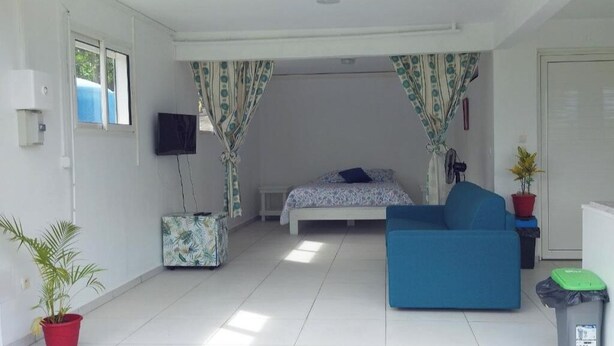 Ein Schlafzimmer mit einem Bett, einem blauen Sofa, einem Fernseher und Vorhängen.