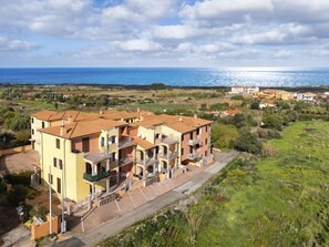 Ein Wohngebäude mit mehreren Balkonen, einer gepflasterten Auffahrt und Blick auf das Meer.