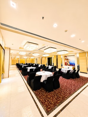 A conference room with multiple tables and chairs, a patterned carpet, and a decorative wall mural.