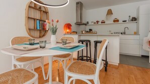 Eine moderne Küche mit weißen Schränken, einem runden Holztisch mit vier Stühlen und einer Pendelleuchte.