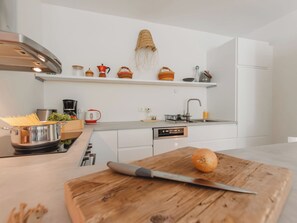 Een koelkast, een oven, een vaatwasser, kookgerei, borden en bestek