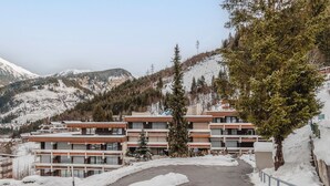 Ein modernes, mehrstöckiges Hotel mit einer Skipiste im Hintergrund.