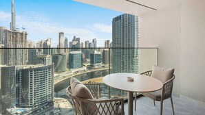 Un balcon doté d’une balustrade en verre, offrant une vue sur un paysage urbain avec des bâtiments modernes et une rivière.