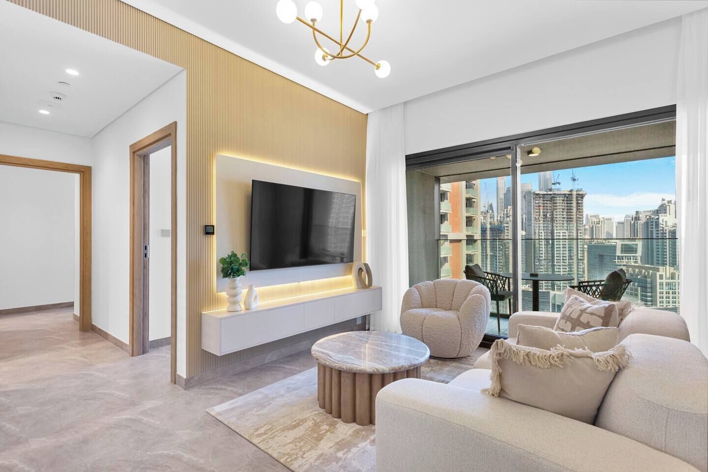 A modern living room with a flat-screen TV, comfortable seating, and a city view.