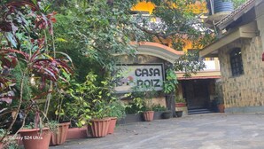 Ένα κτίριο με την επιγραφή «CASA ROZ», με πρόσοψη από πέτρα, γλάστρες με φυτά και μια πύλη στην είσοδο.