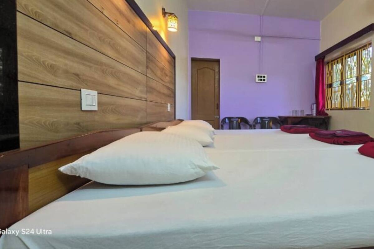 Una habitación de hotel con una cama grande, cabecera de madera y pared morada.