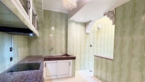 Una cocina moderna con encimera de granito, armarios blancos y una lámpara decorativa en el techo.