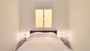 Un dormitorio con cama, ventana y dos lámparas de noche.
