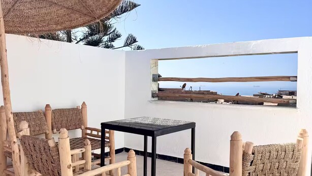 Una terraza con mobiliario de mimbre, una mesa y vistas al mar.