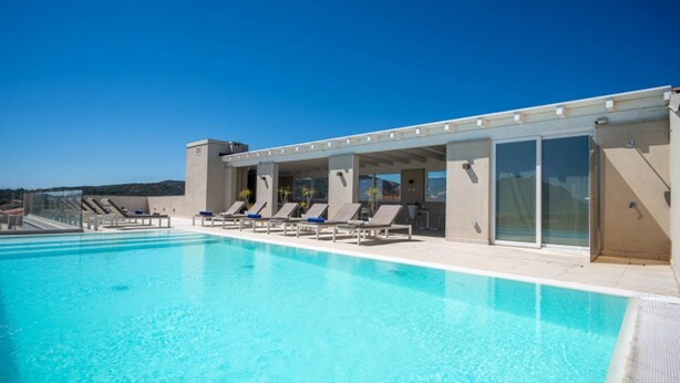 A swimming pool with lounge chairs and a covered area with glass doors. - A cozy space ideal for two people, designed for comfort and tranquility. The sleeping area can be arranged with a double bed or twin beds, depending on the guests' needs.Most units feature a veranda or garden furnished with a table and chairs, perfect fo (Porto San Paolo)