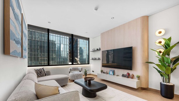 Een moderne woonkamer met een groot raam, een flatscreen televisie, een bank, een bijzettafeltje en een kamerplant.