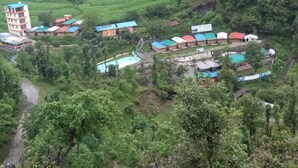 A rural area with a cluster of colorful buildings, including a multi-story structure and several smaller houses with distinct roofs. - Nature Walk Resort Mussoorie (Mussoorie)