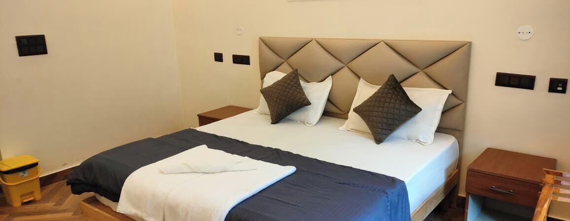 A neatly made bed with a headboard, two bedside tables, and a small wooden chair.