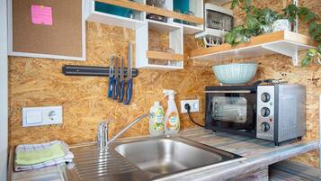 A kitchen with a built-in sink, a toaster, and shelves with jars and plants.