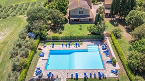 An aerial view of a property with a swimming pool, lounge chairs, and a stone building surrounded by greenery. - Apartment 'Appartamento 9' with Shared Pool and Shared Garden (Lajatico)