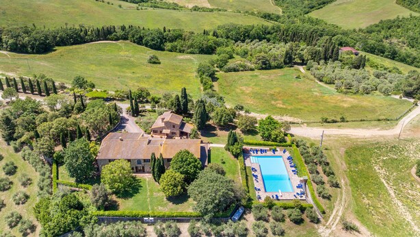 A villa with a swimming pool surrounded by lush greenery and hills. - Apartment 'Appartamento 9' with Shared Pool and Shared Garden (Lajatico)