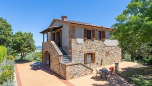 Une maison en pierre dotée d’un balcon, d’un espace extérieur aménagé et offrant une vue sur la campagne.