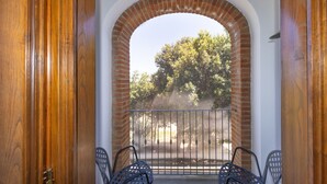 Une porte en arc donnant sur des arbres et ornée d’une rambarde en métal.