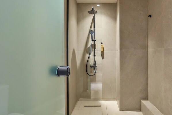 Un baño moderno con cabina de ducha de vidrio, ducha de mano y rociador manual.