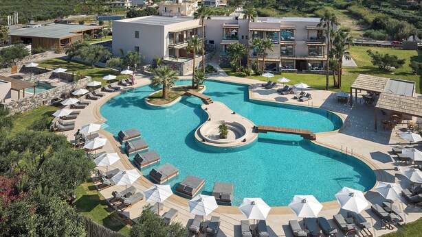 A resort with a large swimming pool, sun loungers, and a view of the sea. - Sentido Amounda Bay (Malevizi)
