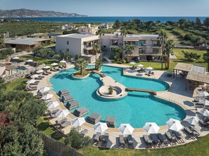 Un resort con una amplia piscina, tumbonas y vistas al mar.