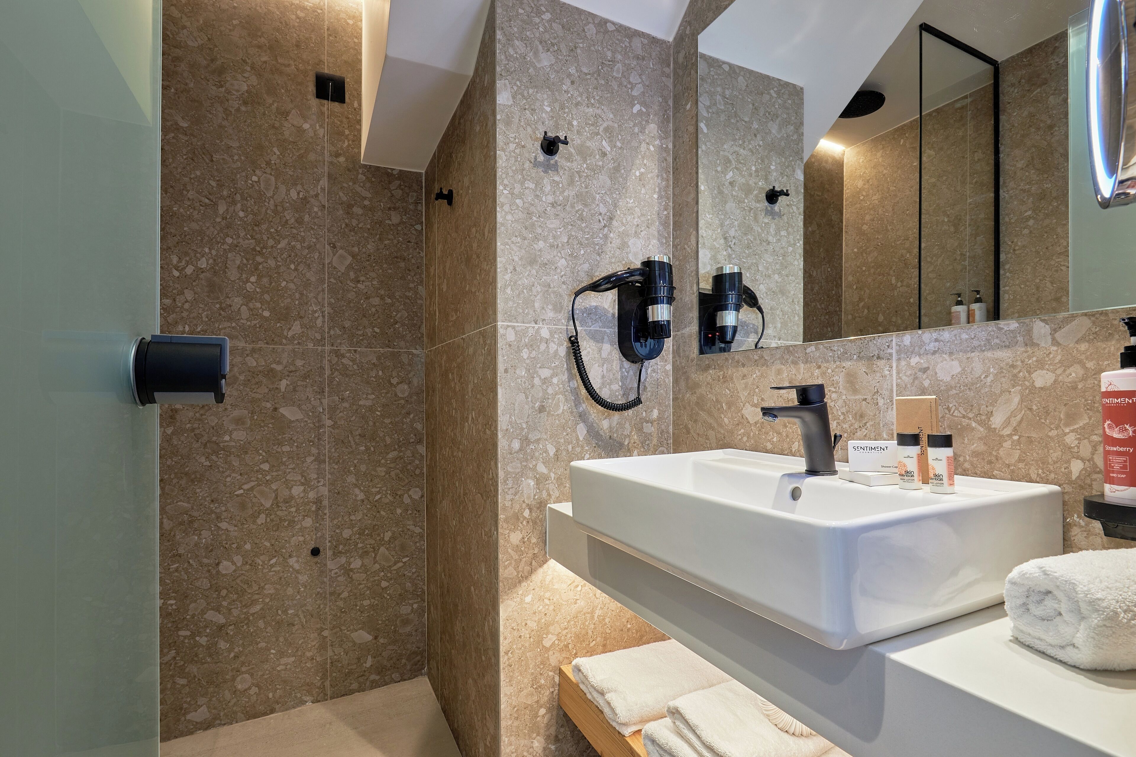 Ein modernes Badezimmer mit großem Spiegel, Waschbecken in Weiß und einer Duschkabine.