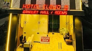 Een hotel genaamd 'Hotel Cloud 9' met een bord waarop 'Feestzaal / Kamers' staat, en een bordje met de tekst 'Kamers geopend'.