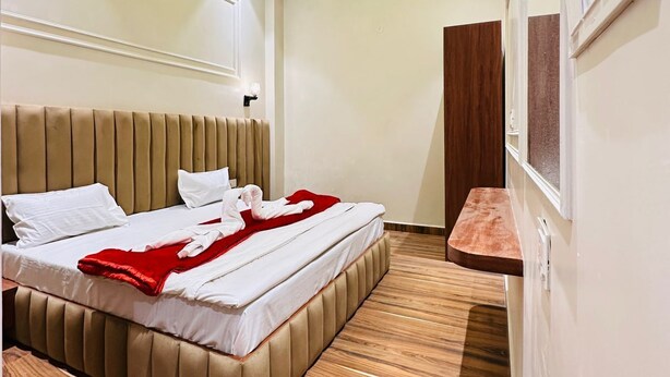 Een moderne hotelkamer met een groot bed, houten vloeren en een plafond met ingebouwde verlichting.