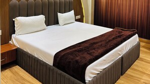 Een moderne slaapkamer met een groot bed, een wand van houten panelen en inbouwspots.