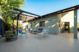 Un patio con pérgola, asientos y una planta en maceta.