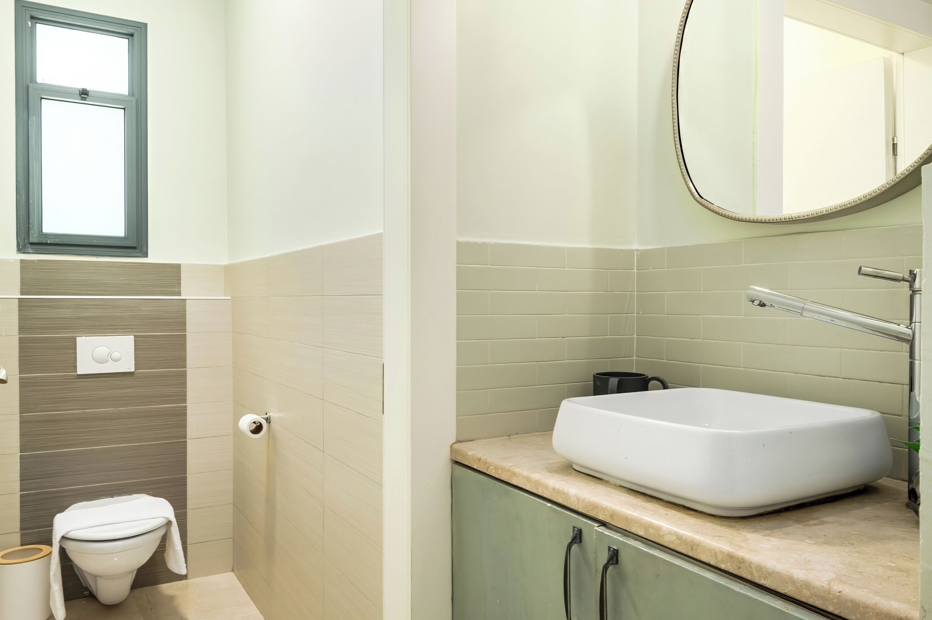 Ein Badezimmer mit Toilette, Waschbecken, Spiegel und Fenster.
