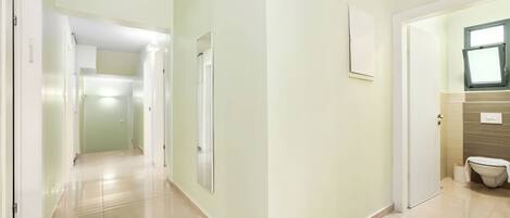 Un pasillo con un inodoro y un espejo en la pared.