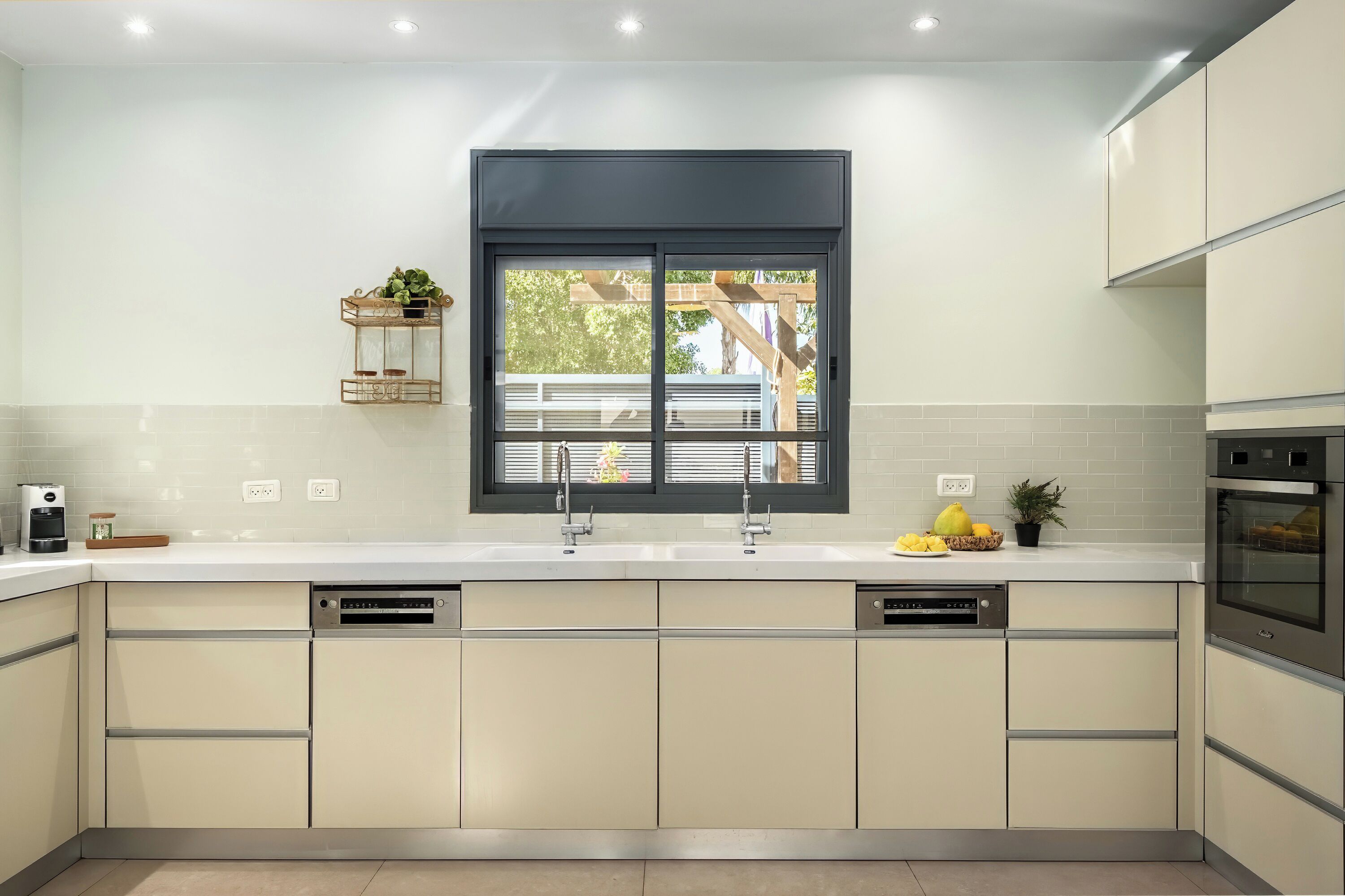 A modern kitchen with a large window, white countertops, and stainless steel appliances.