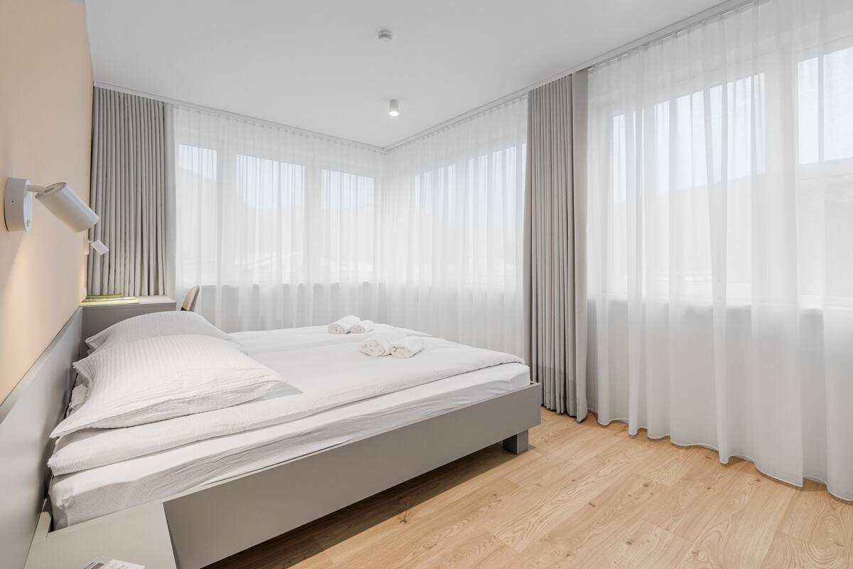 Une chambre moderne avec un grand lit, des rideaux légers et un plancher en bois.