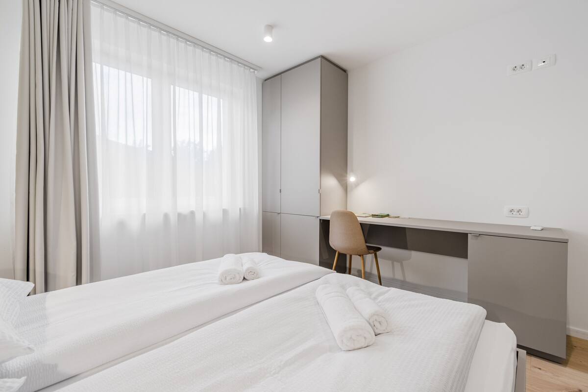 Une chambre d’hôtel moderne avec deux lits, un bureau et une chaise.