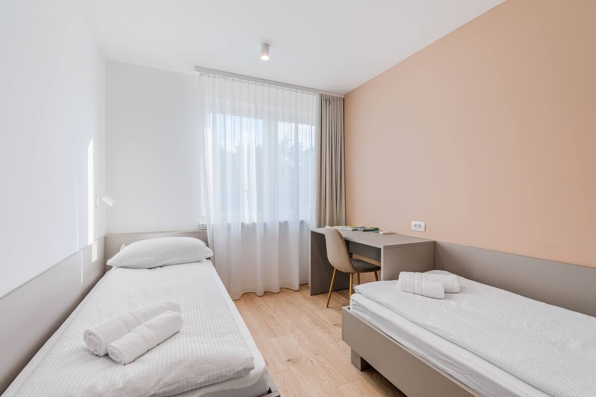Une chambre d’hôtel avec deux lits simples, un bureau et une chaise.