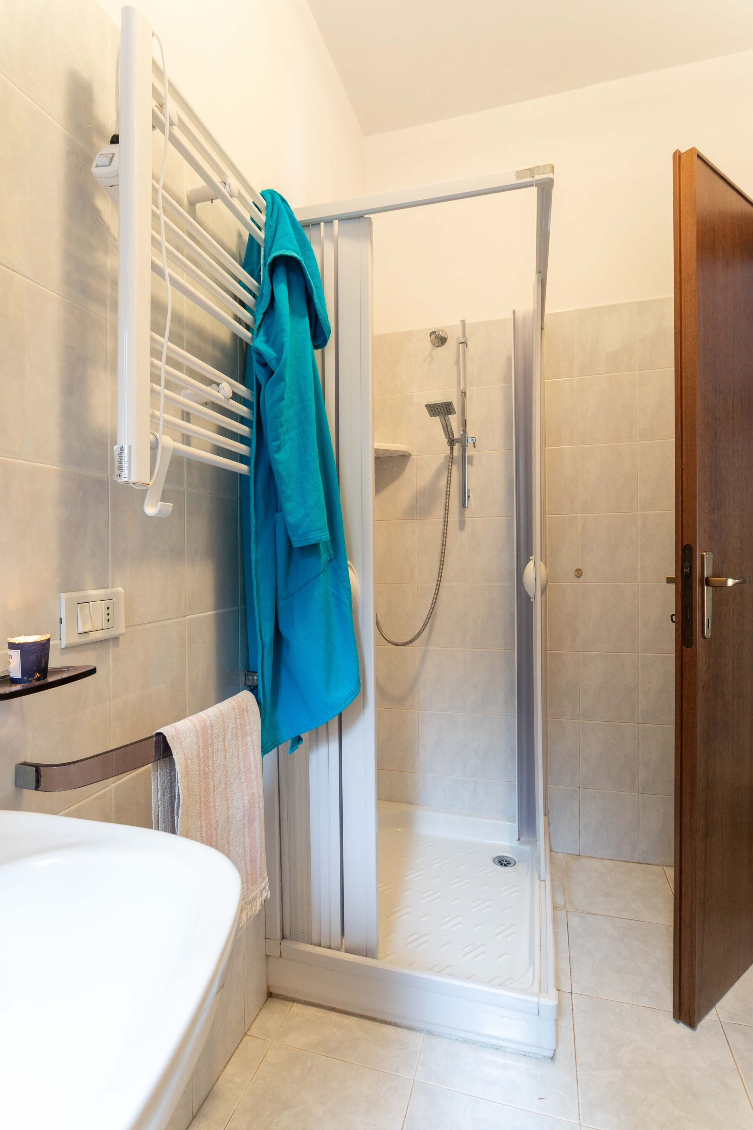 A bathroom with a shower, a bathtub, and a towel rack.